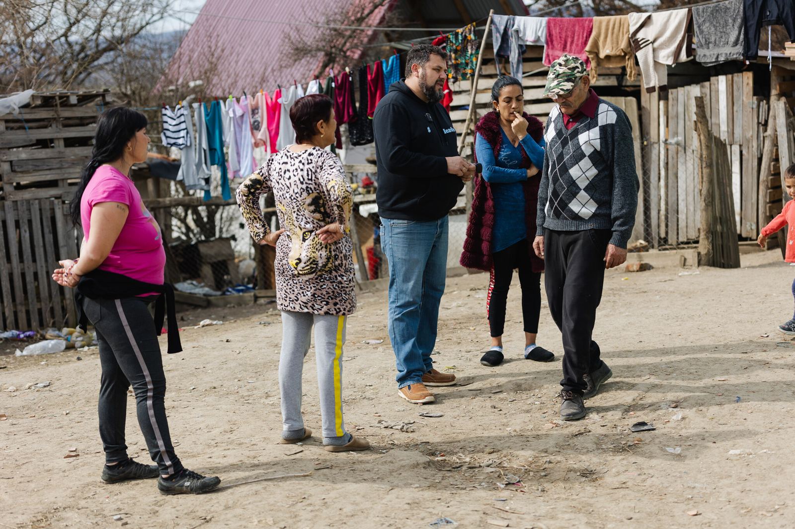 Staff talking with residents outside their homes in the settlement, washing hung out to dry