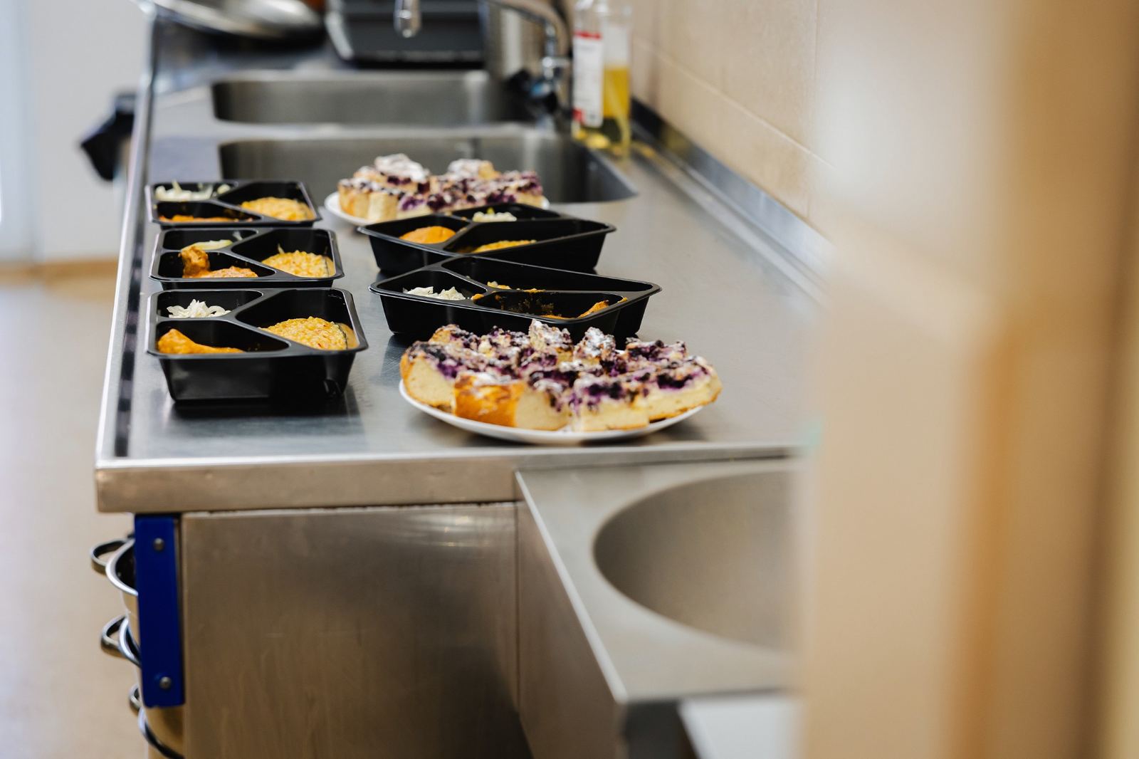 Boxed meals and pastries laid out along a stainless steel kitchen counter