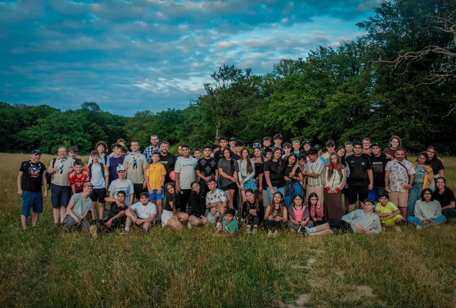 A large group of volunteers and staff in a meadow under a dramatic sky