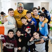 A staff member with a group of boys crowding around him in the day centre