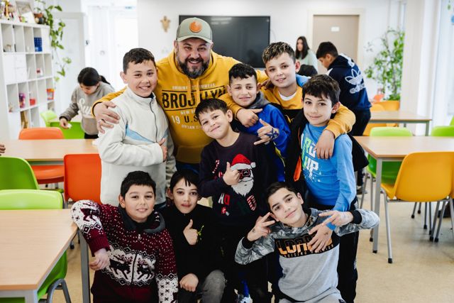 A staff member surrounded by a group of grinning boys in the day centre